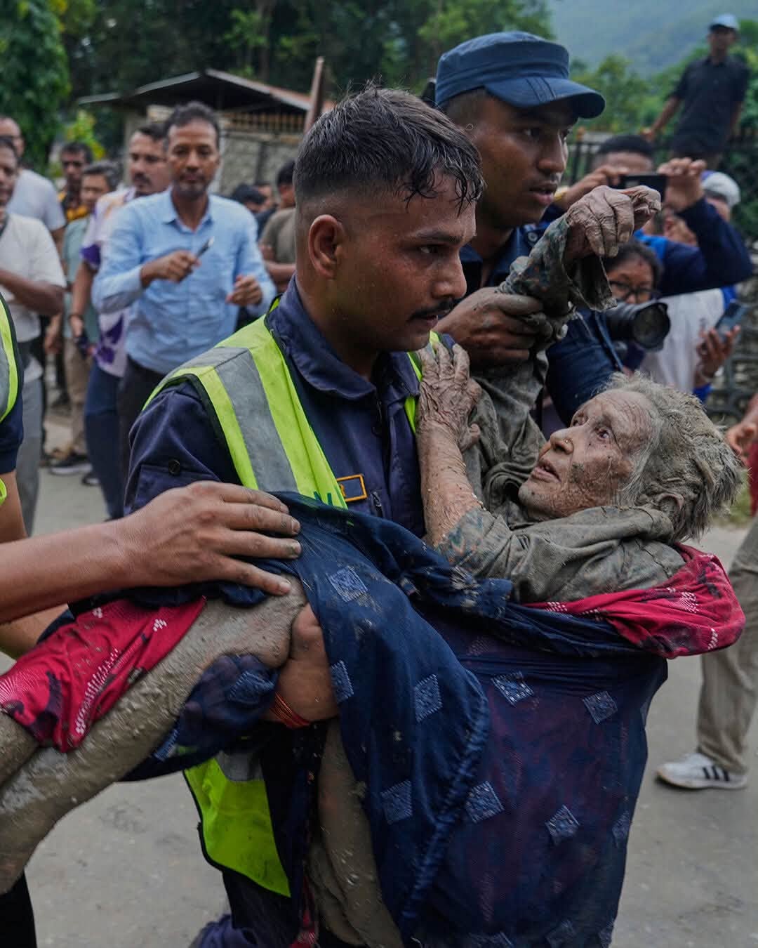 A rescue worker carries an elderly flood survivor to safety in Nepal.