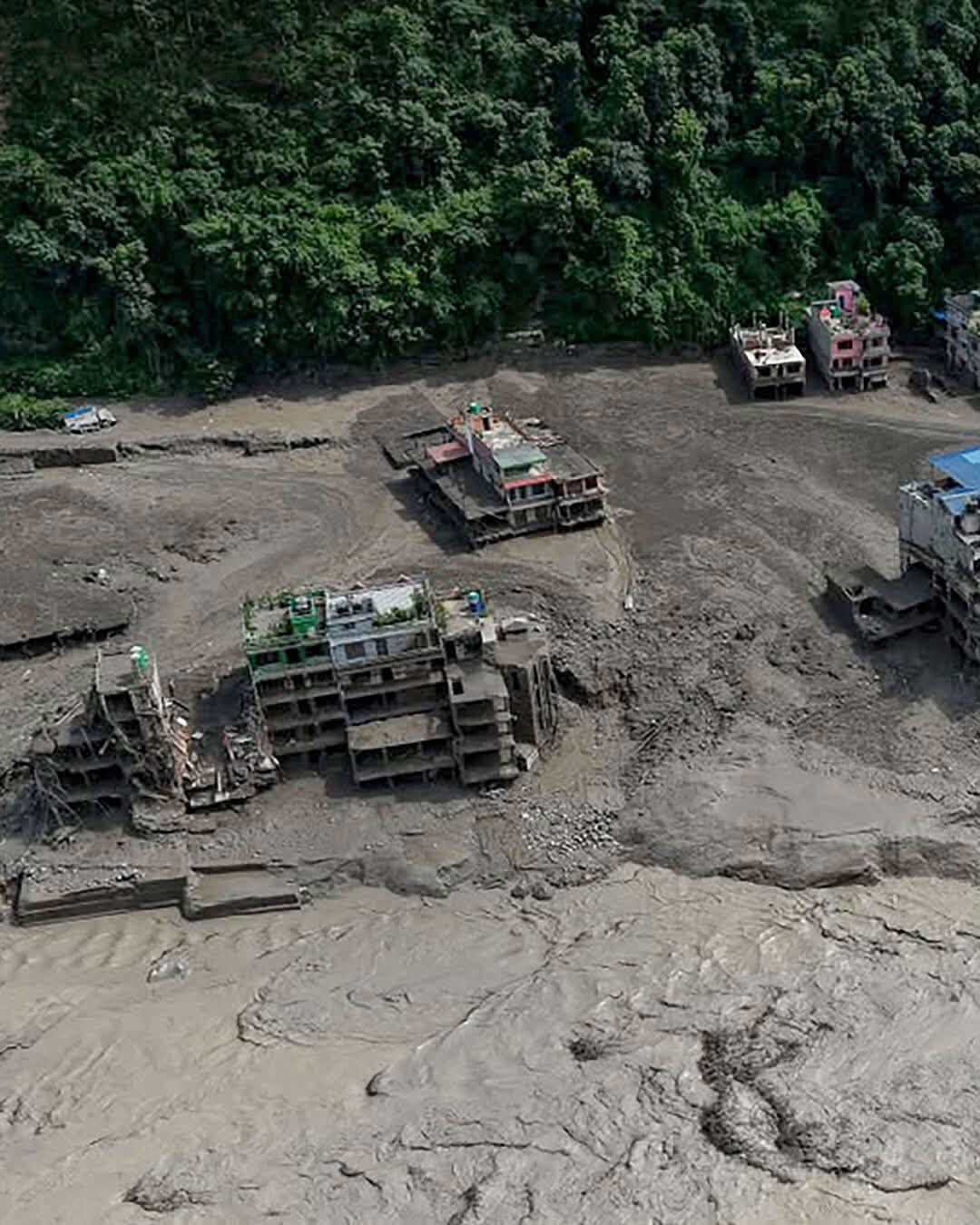 Multi-story buildings partially buried and destroyed by mud.